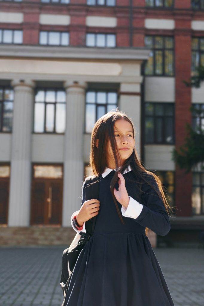 Schoolgirl is outside near school building